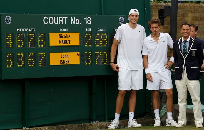 John Isner (links) en Nicolas Mahut staan bij het scorebord na hun marathonpartij in 2010 op Wimbledon.