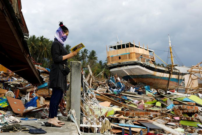 Een vrouw leest de koran, bij de restanten van een huis dat verwoest werd door de tsunami.