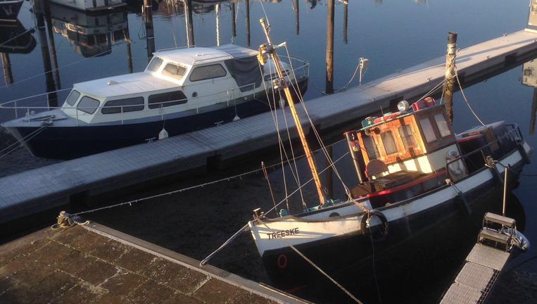 Boot ligt scheef in jachthaven Grave door gezakt waterpeil in de Maas. Beeld Peter de Graaf