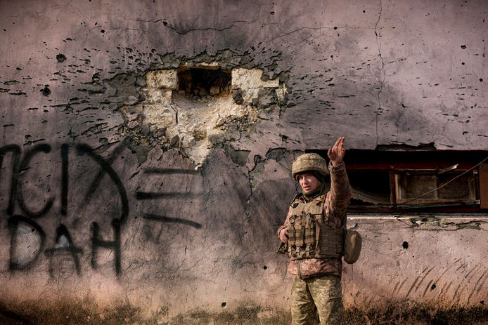 Een beschoten huis in de Luhansk regio in het oosten van Oekraïne. Een Oekraïense militair wijst aan uit welke richting de granaat kwam
