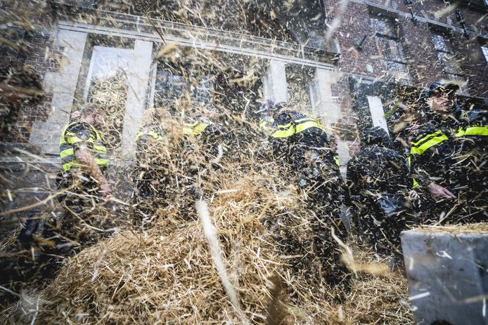Politieagenten werden maandag in Groningen met stro bekogeld tijdens het boerenprotest voor het provinciehuis.