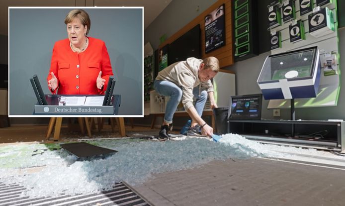 Een werknemer van een telefoonwinkel veegt de glasscherven van zijn compleet vernield uitstalraam bij elkaar. Veertig winkels zijn in de nacht van zaterdag op zondag beschadigd, een deel is geplunderd. Inzet: Duits bondskanselier Angela Merkel.
