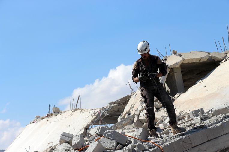 Vrijwilligers van de Witte Helmen zoeken in september 2017 onder het puin naar overlevenden van een luchtaanval op Armanaz, in het noorden van Syrië.  Beeld EPA