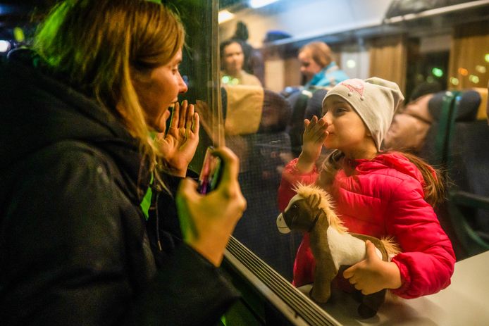 Een Oekraïens meisje zwaait naar een achterblijver op het station van Boekarest als ze verder reist in de richting van Hongarije.