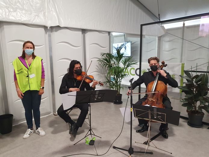 Vrijwilligster Heidi De Smedt is blij dat ze vandaag haar shift aan het podium van de vermaarde cellist Christophe Bunzendahl en violist Pedro Pozos mag draaien: "De muziek is naast het vaccin een indicatie naar het Rijk Der Vrijheid."