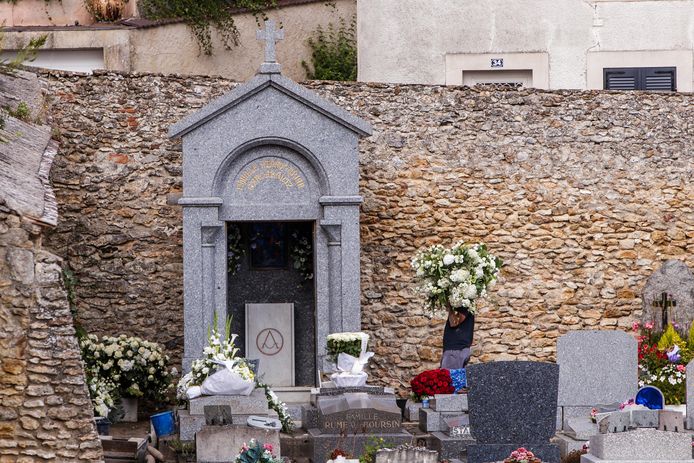 Een man draagt bloemen naar het graf van Aznavour.