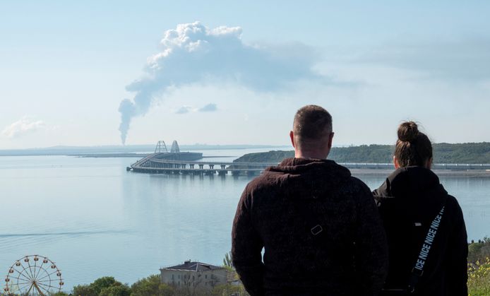 People watch smoke rising from an oil depot in Volna.