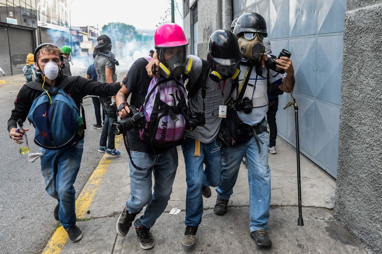 Een verwonde journalist wordt te midden van protesten in Venezuela in veiligheid gebracht. Beeld AFP