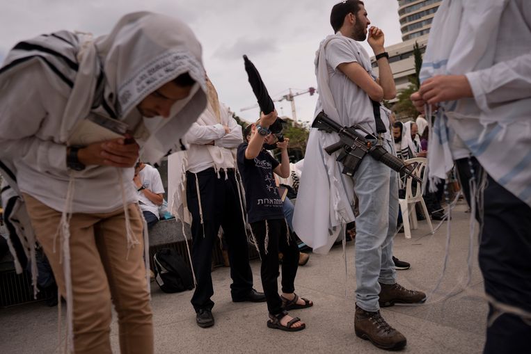 Joodse mannen tijdens een gebedsbijeenkomst in Tel Aviv, met gewapende bewaking.  Beeld AP