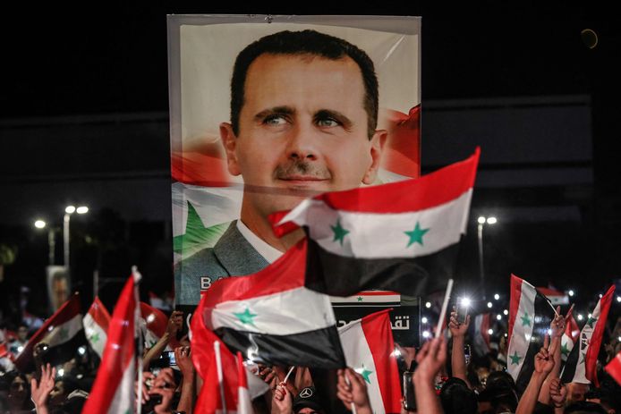 Des Syriens brandissent des drapeaux nationaux et un grand portrait de leur président alors qu'ils célèbrent dans les rues de la capitale Damas, au lendemain d'une élection destinée à donner un quatrième mandat à l'actuel président Bachar el-Assad, le 27 mai 2021.