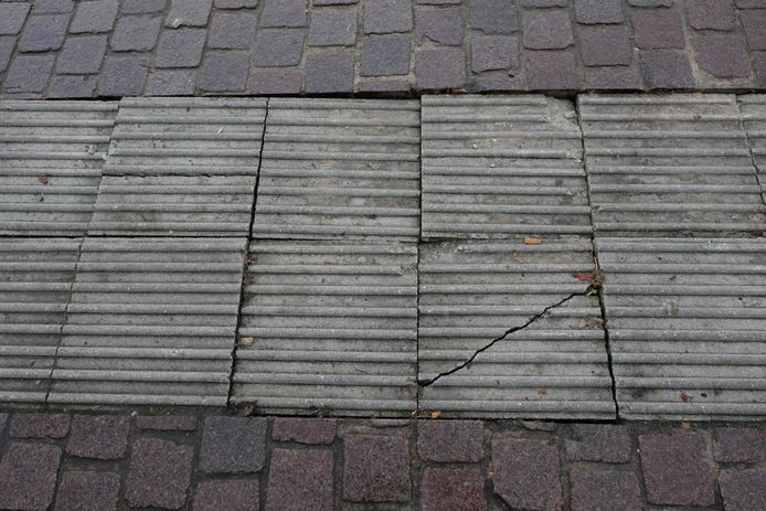 De beschadigde blindengeleidestrook wordt hersteld.