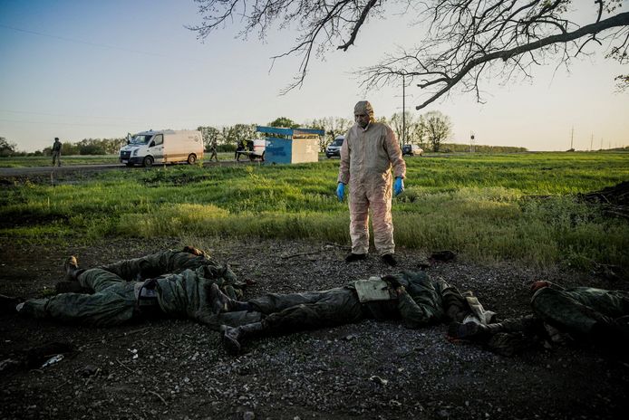 Een man kijkt naar de lichamen van enkele gesneuvelde Russische soldaten.