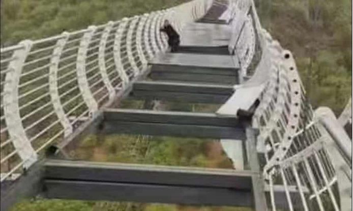 Chinese toerist houdt zich stevig vast aan de brug nadat de glazen panelen zijn neergestort.