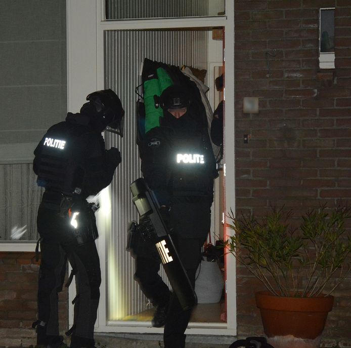 Leden van de Ondersteuningsgroep verlaten het huis nadat de verdachten zijn afgevoerd.
