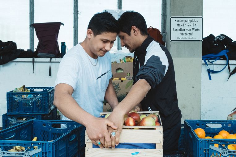 Arif Haidary (rechts) en zijn broer komen uit Afghanistan. Ze helpen bij de voedselbank van München, waar ze zelf ook hulp ontvangen.  Beeld Foto Münchner Tafel, Daniel Booth