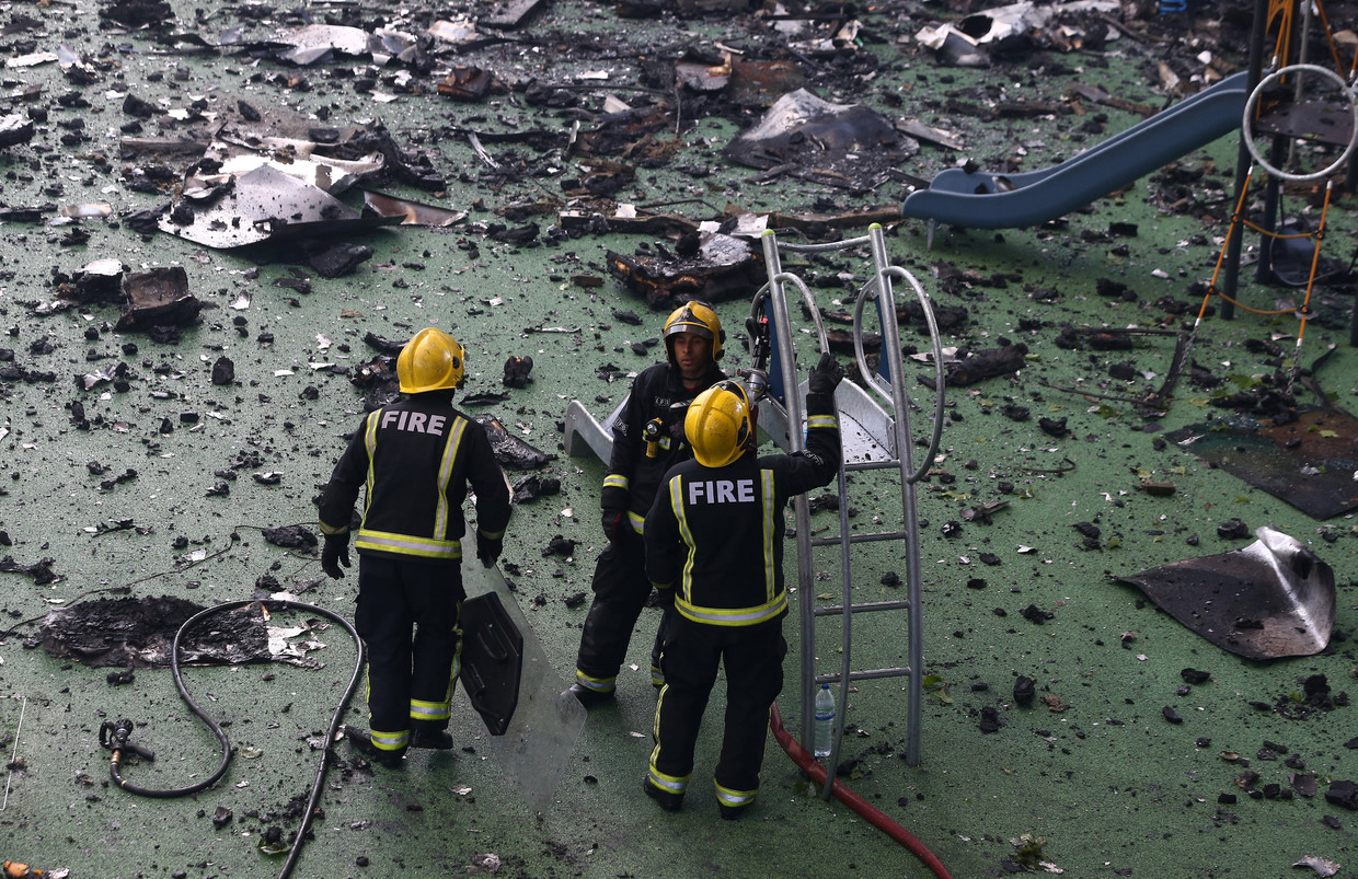 Brandweermannen staan bij een speeltuin die zich naast de Grenfell-toren bevindt. Beeld REUTERS
