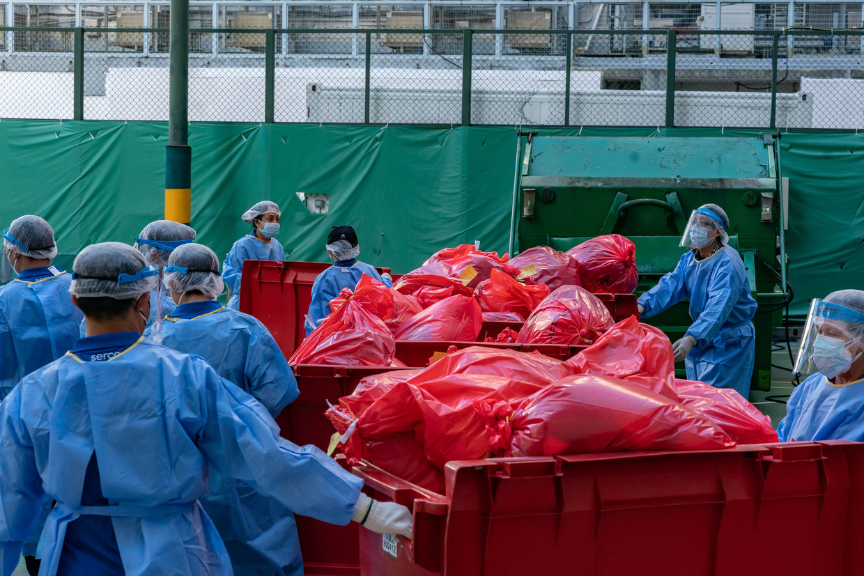 Ziekenhuismedewerkers in Hongkong zetten containers met medisch afval buiten. 