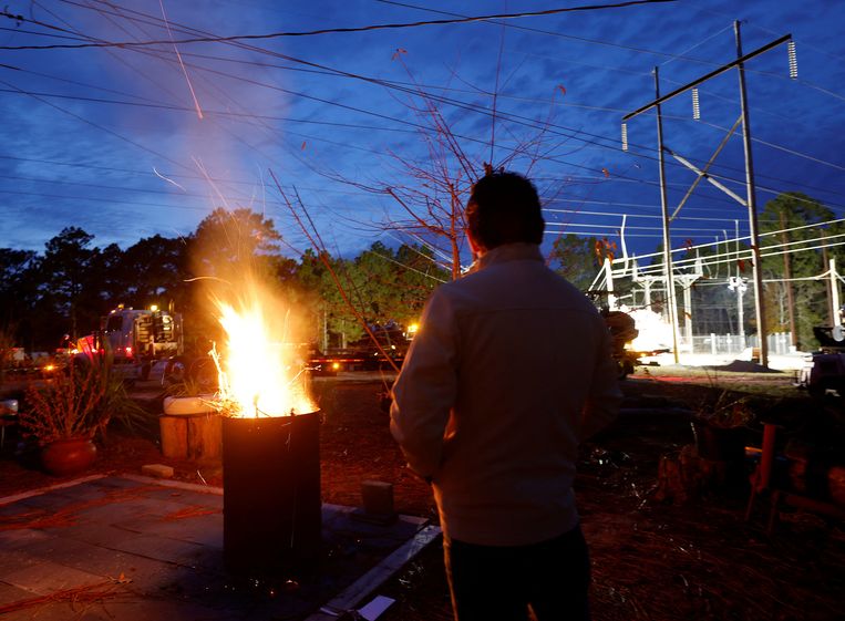 Een man warmt zich op bij een vuurtje naast een energiestation in Moore County, North Carolina. Zaterdagavond viel in het district de stroom uit door een gewapende aanval op het stroomnetwerk. Beeld Reuters