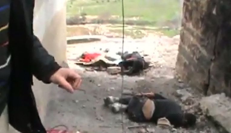 Een still uit een video die op 6 februari op YouTube werd geüploaded. Een Syrische man wijst naar de dode lichamen van drie mensen die werden gedood tijdens beschietingen op de wijk Rastan.<br /> Beeld afp