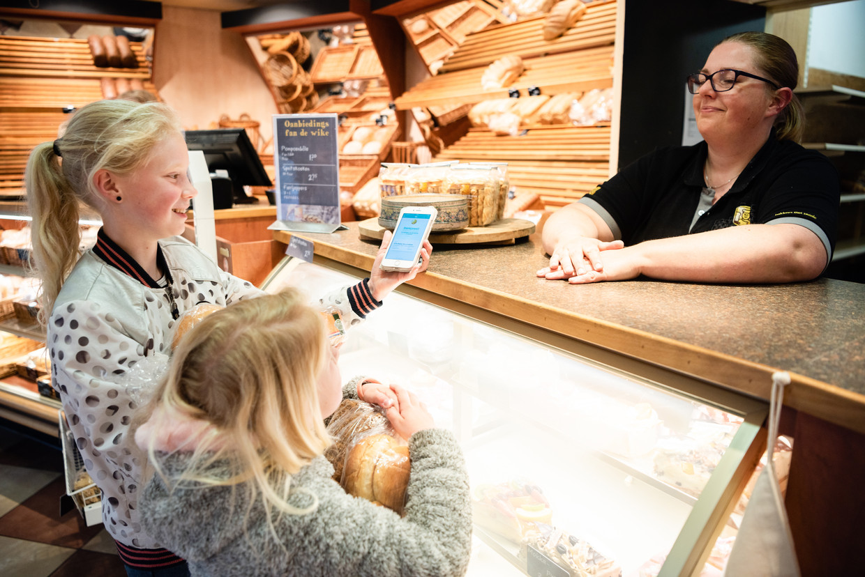 Twee zusjes halen met hun moeder (buiten beeld) bij Bakkerij de Groot in Stiens een op TooGoodToGo geplaatste zak met brood en gebak op.  Beeld Katja Poelwijk
