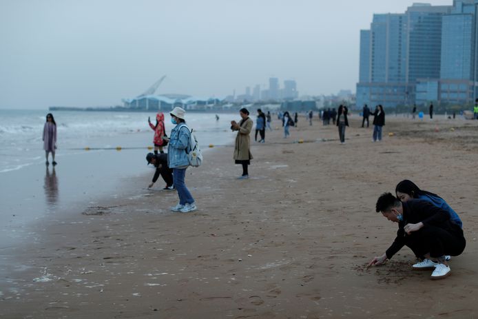 Inwoners van Qingdao genieten van een strandwandeling één dag na het ongeval in de Gele Zee.