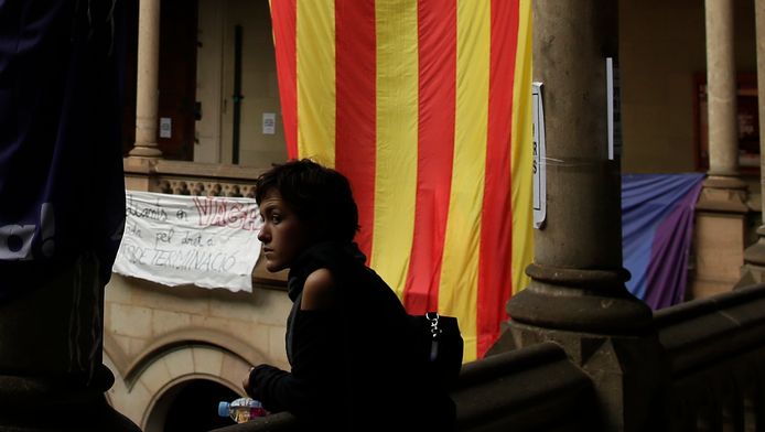 Een studente in de universiteit van Barcelona met achter haar een Catalaanse onafhankelijkheidsvlag.