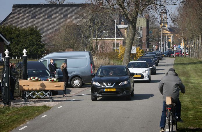 Nabestaanden nemen vanuit de auto afscheid van de overledene. Wegens de coronacrisis zijn er niet meer dan 30 mensen welkom bij begrafenissen.