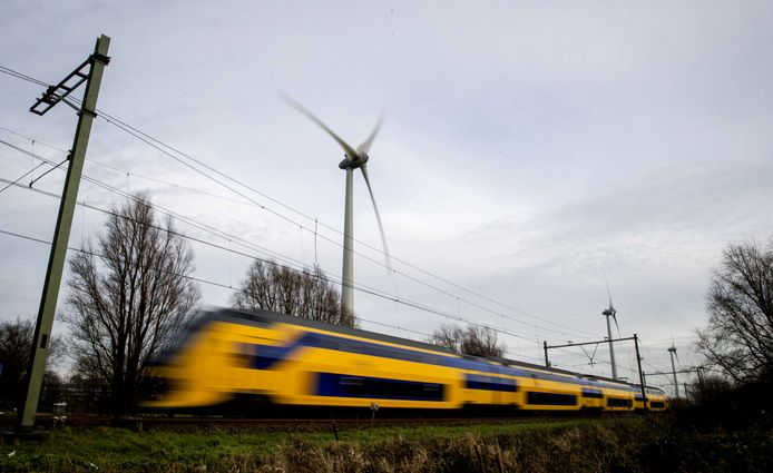 Een NS-trein passeert een windmolen