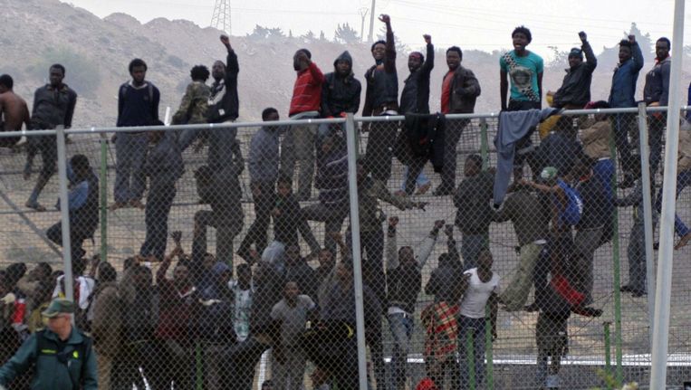 Tientallen immigranten klimmen over het hek bij de grens tussen Marokko en en de stad Mellila in Spanje, mei 2014. Beeld epa