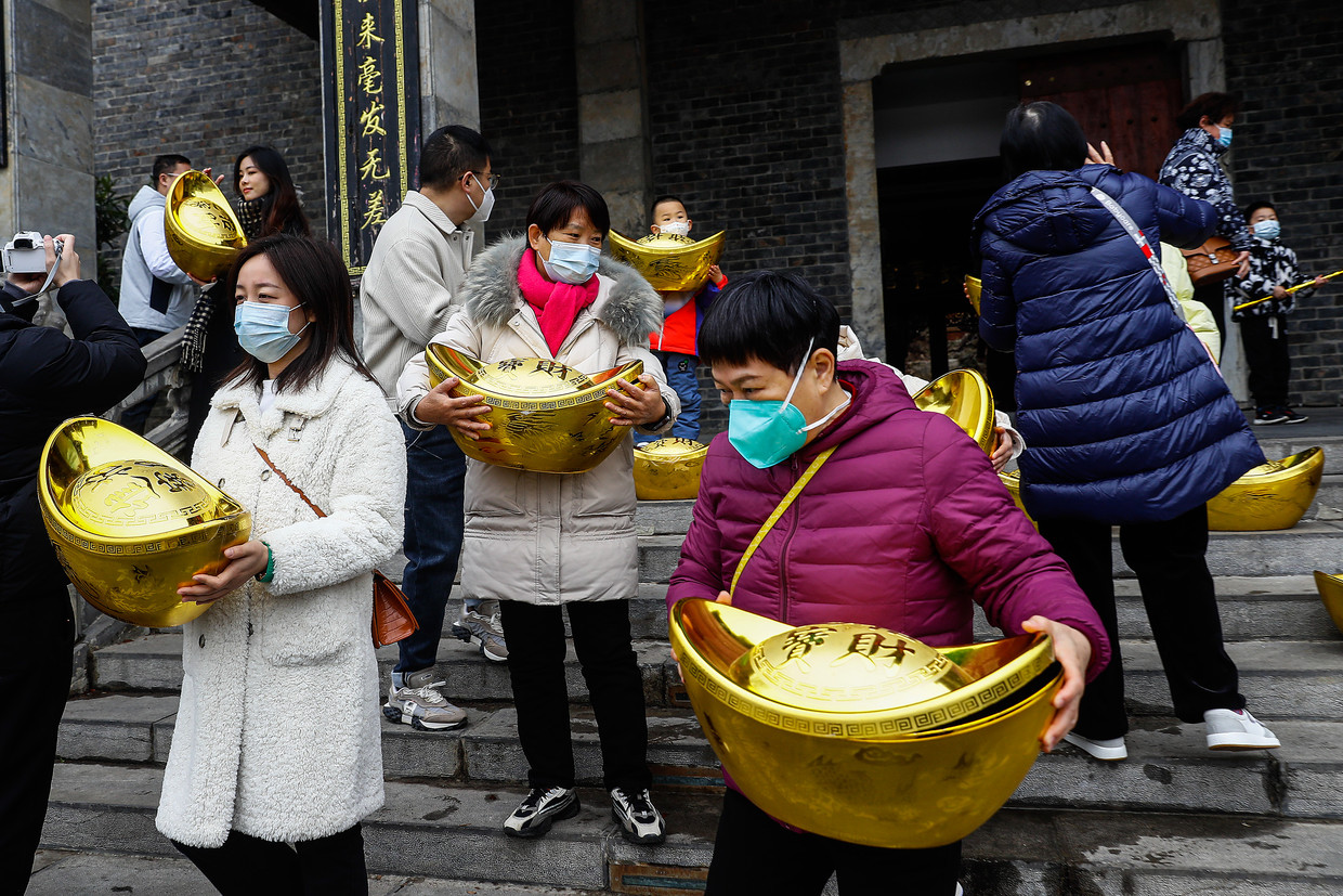 Mensen poseren met nagemaakte gouden baren, een symbool voor welvaart en voorspoed, bij de Expo Garden in Wuhan op 22 januari 2023.  Beeld Getty Images