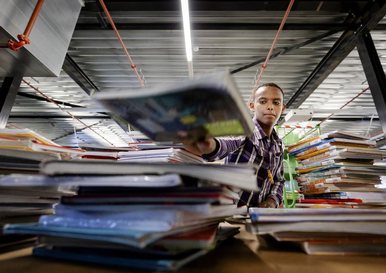 Een vakantiewerker sorteert boeken bij uitgeverij Van Dijk Education in Kampen. Beeld ANP 