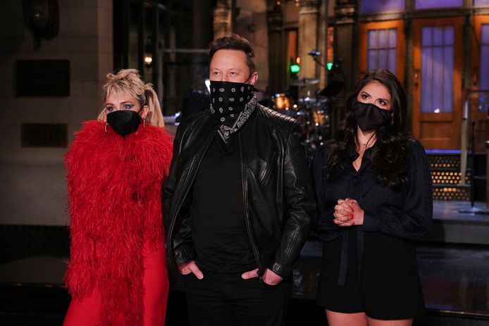 Musk tijdens het tv-programma geflankeerd door Miley Cyrus (links) en Cecily Strong van Saturday Night Live.