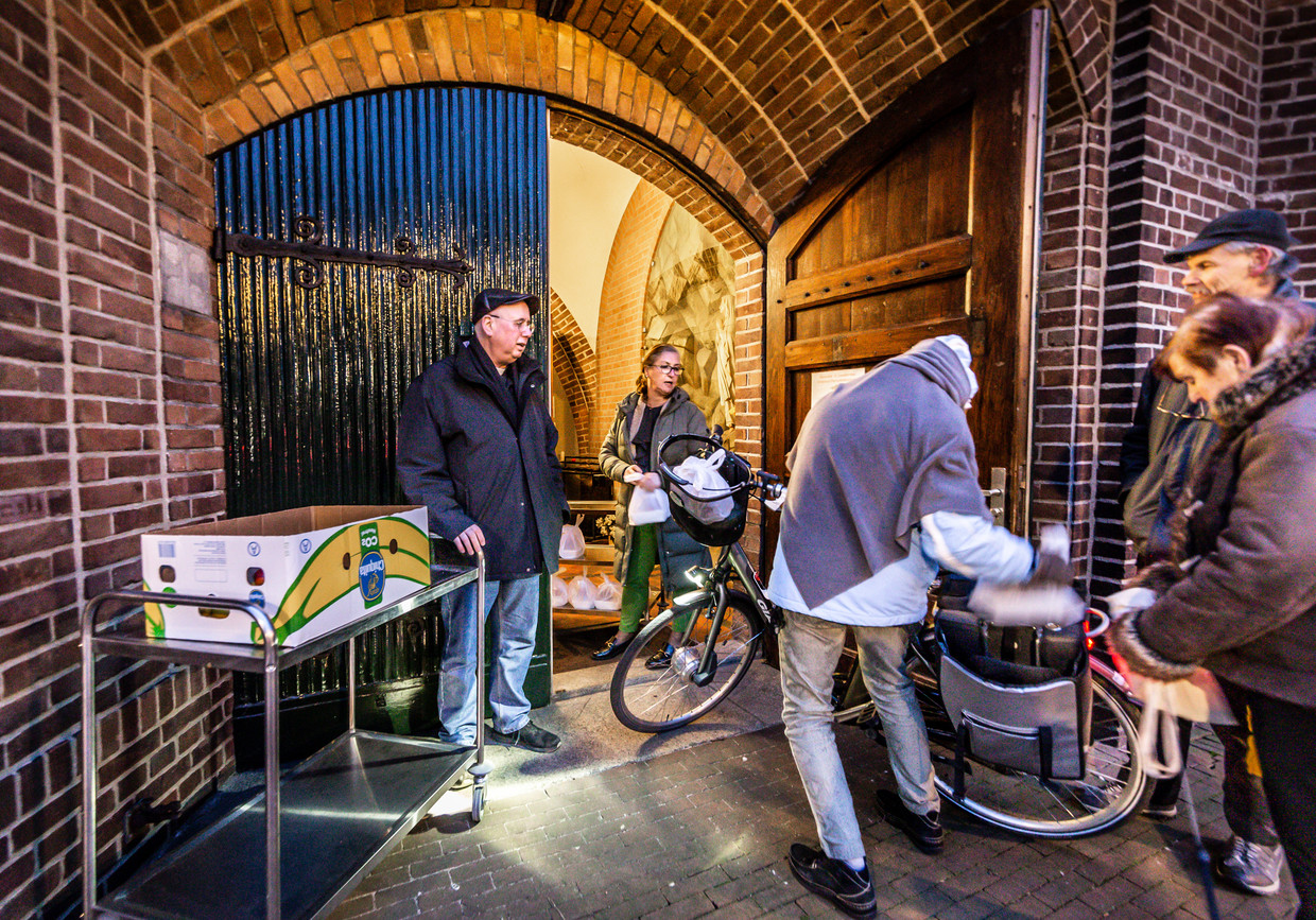 Pastoor Erik Seidel (links) van de Lambertus-parochie deelt met een vrijwilliger gratis afhaalmaaltijden uit in Helmond. Beeld Roger Dohmen