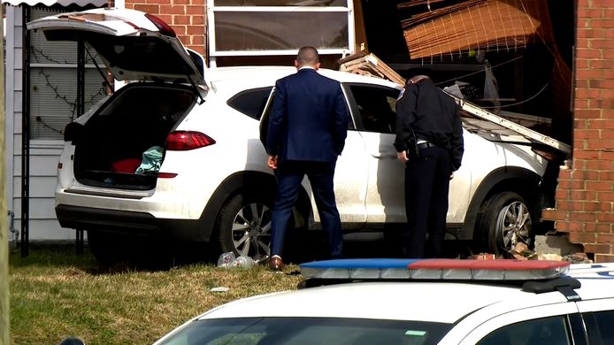 Inspecteurs onderzoeken het voertuig dat tegen een huis botste na de schietpartij.