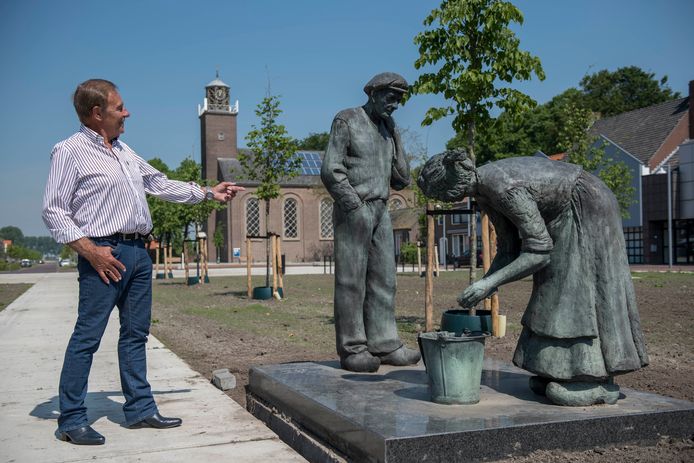 Dorpsraadvoorzitter Lau Oosthoek van Schoondijke, bij het beeld Landarbeiders van Jan Haas. Het standbeeld heeft een plekje aan het Dorpsplein gekregen.