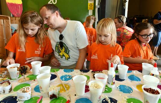 Een vader begeleidt kinderen tijdens het plakken van de zaden.