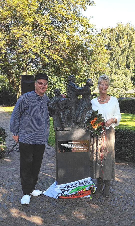 Voorzitter Gerrit Mollink van de Folkloristische Dansgroep Hellendoorn en cultuurwethouder Anja van den Dolder bij het beeldje, waarop de plaquette is aangebracht.