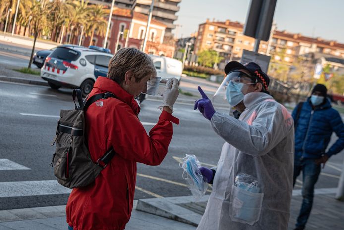 Een vrouw krijgt in het treinstation van Girona een mondmasker van een civiele agent.