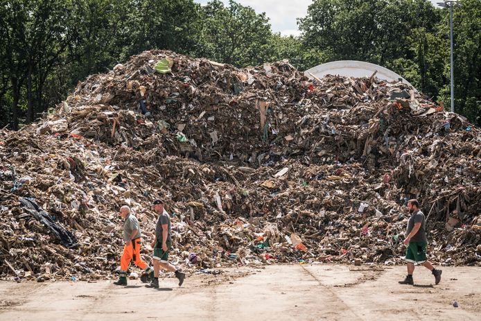 Des hommes passent devant une pile de déchets au centre de gestion des déchets, une installation de stockage provisoire pour les déchets encombrants provenant des régions inondées de la vallée de l'Ahr, à Niederzissen, en Rhénanie-du-Nord-Westphalie, dans l'ouest de l'Allemagne, le 30 juillet 2021.