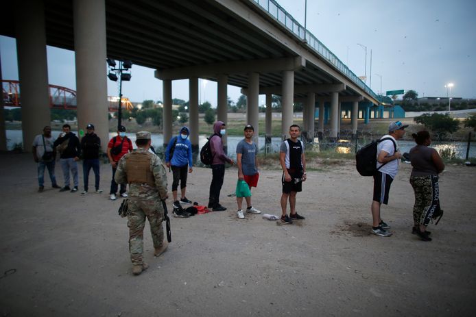 Migranten die de grens met de VS hebben overgestoken wachten op agenten van de grenspatrouille.