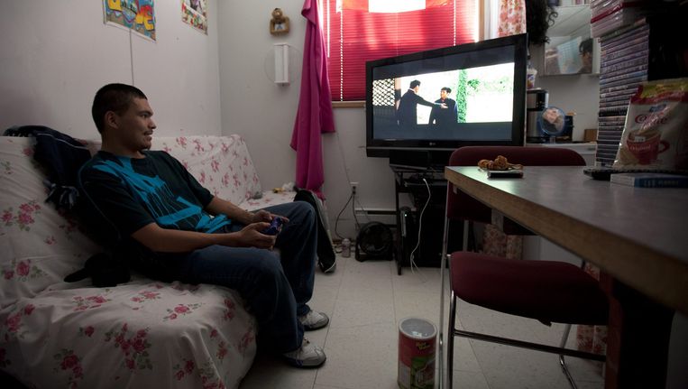 Een inwoner van Attawapiskat kijkt televisie in zijn trailer. Beeld Belgaimage