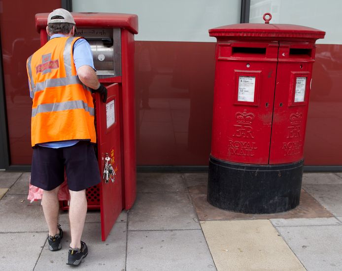 Een postbode haalt een brievenbus leeg in Londen. Archiefbeeld.