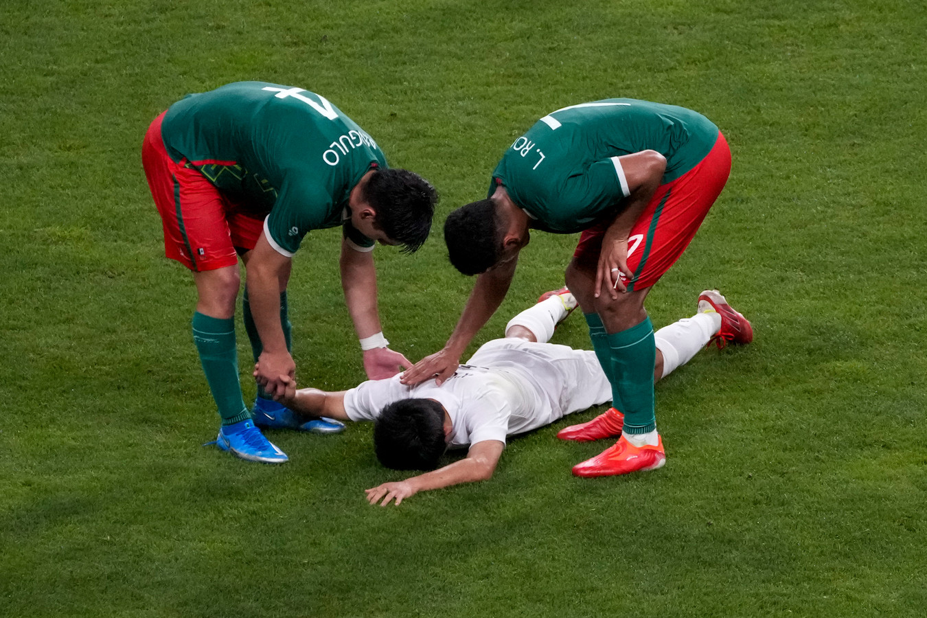 De Mexicaanse voetballers Jesus Angulo en Luis Romo troosten Japanner Takefusa Kubo na de troostfinale in het voetbaltoernooi.