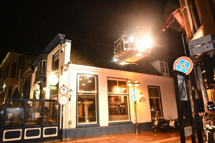 Met behulp van een hoogwerker maken brandweerlieden de losgewaaide dakdelen weer vast.