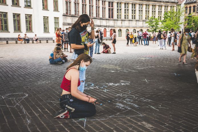 Mensen laten boodschappen achter in krijt tijdens een wake in Gent.