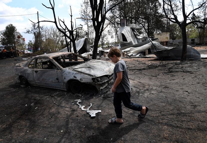 De 8-jarige Jarrod McInnes wandelt naast het huis dat zijn familie wilde kopen, maar volledig vernietigd werd door de bosbrand.
