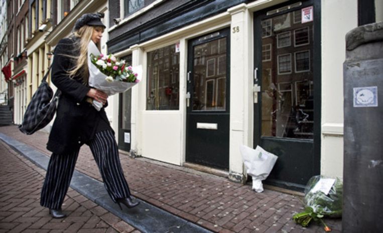 Woordvoerster van De Rode Draad Metje Blaak legt vrijdag bloemen neer bij de peeskamer aan de Oudezijds Achterburgwal in Amsterdam waar in de nacht van donderdag op vrijdag een 19-jarige prostituee om het leven kwam. Foto ANP/Koen van Weel Beeld 