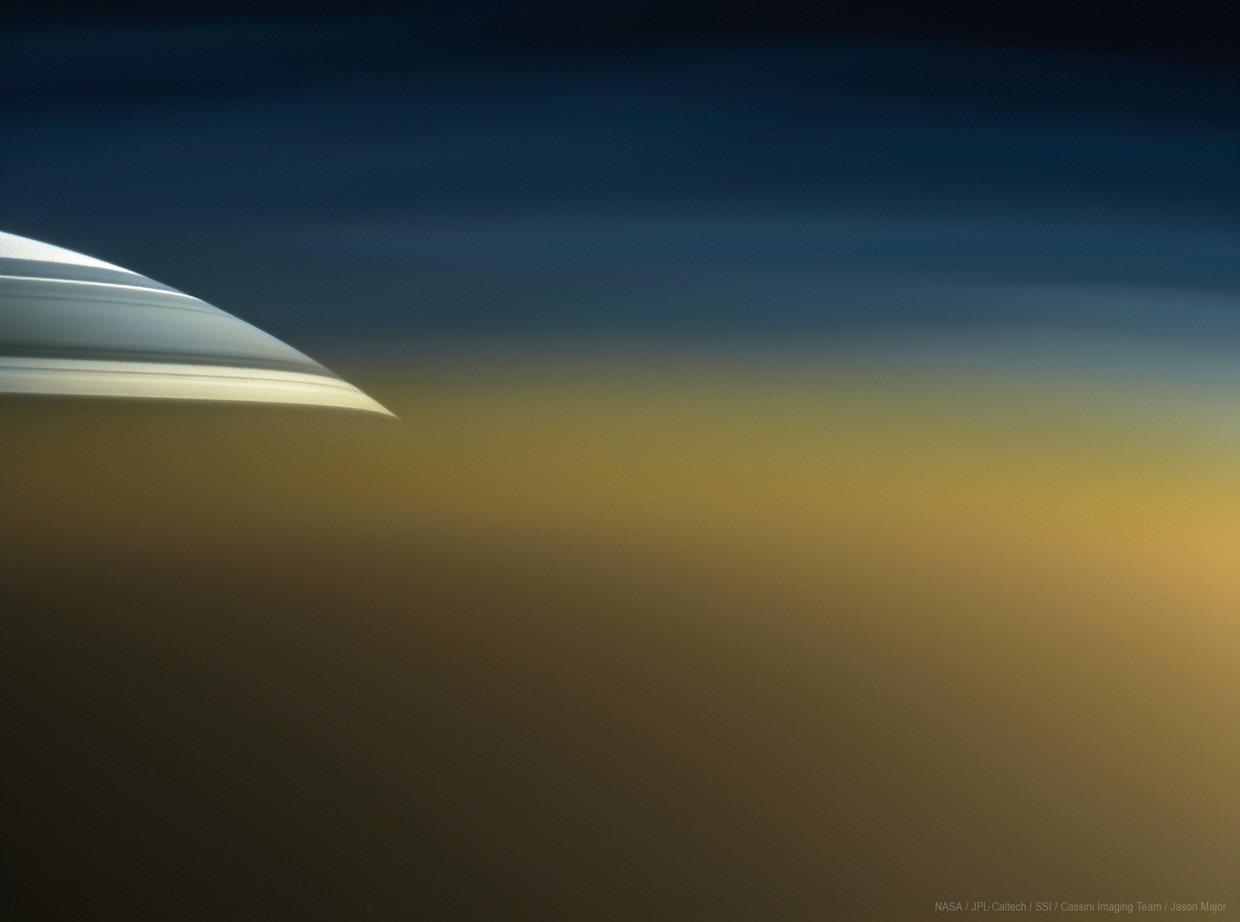 De planeet Saturnus (boven), met de schaduw van het ringenstelsel, gezien door de dikke dampkring van de grote Saturnusmaan Titan (voorgrond). Beeld Cassini/beeldbewerking: Jason Major