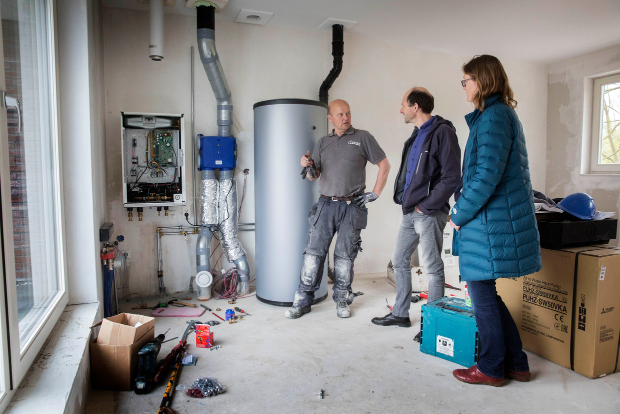 Evert Hassink en Claudia Holstein gaan gasloos wonen. Installateur Hans van der Kamp is bezig met het aansluiten van de pompinstallatie. In het midden de boiler van 300 liter. Beeld Werry Crone