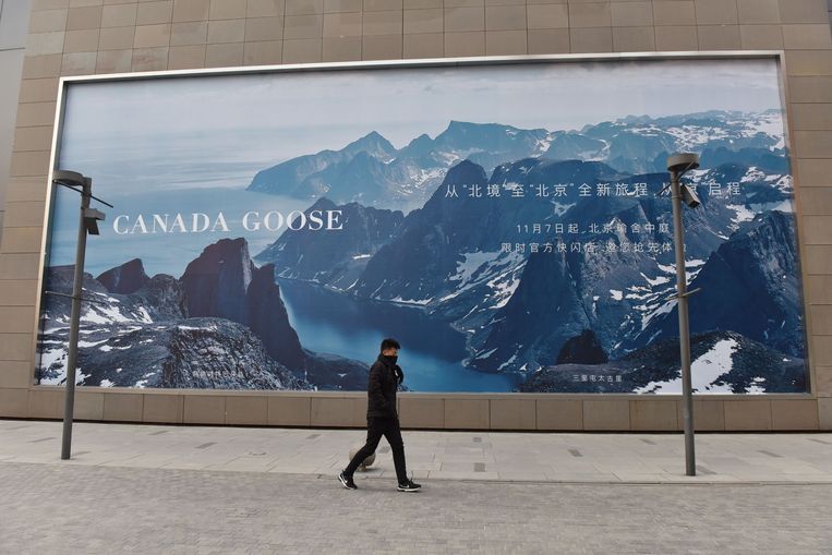 Een man wandelt langs een billboard van Canada Goose vlak bij de nieuwe winkel in Peking. De Canadese parkafabrikant stelde de opening van de winkel uit ten tijde van de diplomatieke rel om de Huawei-topvrouw. Beeld AFP